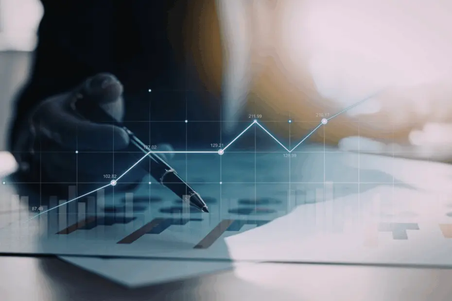 Mão segurando uma caneta sobre documentos financeiros, com gráfico de linhas e barras sobreposto indicando crescimento e evolução de indicadores ao longo do tempo.